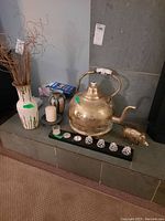 Overall view of lot placed on floor and hearth, showing brass pot, cast pig figure, ceramic vases, pillar candle, candle holder with small candles and decorative pine cone objects.