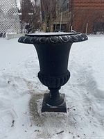 Front view of one planter showing scalloped rim, tapered body, decorative lobed ring and square base