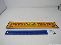 Full view of Lionel Electric Trains metal sign with ruler for scale showing approximately 18 inches length.