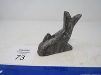 Marble dolphin sculpture shown from a side angle revealing the shape and marble veining.