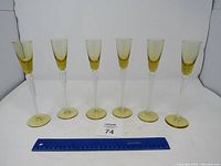 Six yellow-tinted glassware stems arranged side by side showing uniform design and color.