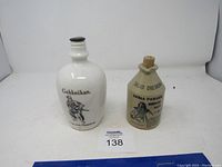Two advertising bottles: a white Gekkeikan ceramic bottle with samurai graphic, and a tan ceramic bottle advertising salad dressing with cork stopper.