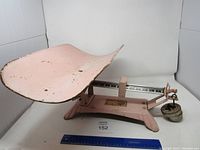 Full view of pink vintage baby scale with curved tray and balance beam mechanism.