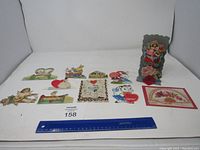 Photo showing full lot of 10 vintage Valentines Day cards laid out flat with a ruler for size reference.