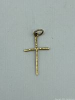 Close-up image of the gold cross pendant showing the hammered texture on front with attached loop.