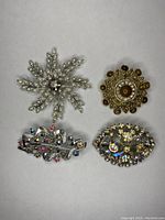 Top view of four brooches showing front designs and rhinestones