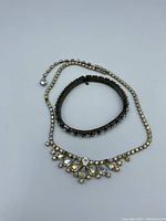 Necklace and bracelet displayed flat on white surface showing the rhinestones and metal details.