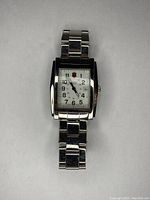 Front view of rectangular-faced wristwatch with white dial and metal link band