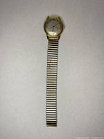 Full front view of a gold-tone vintage watch with silver-tone expansion band, showing the dial, hands, and case.