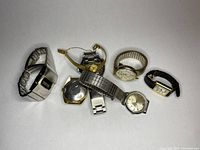 Photo showing all six assorted vintage wristwatches with varied band styles laid out on white background.