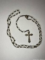 Full view of the entire cross necklace with beaded chain laid out on a white background