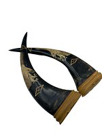 Two black curved decorative horns showing detailed carved scorpion and other patterns, with natural wood bases.