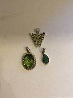 Front view of three green stone sterling silver pendants on white background