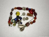 Photo showing a collection of assorted vintage trade beads of various shapes, sizes and colors laid out on a white background.