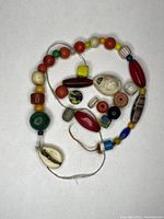 Full view of the string of assorted trade beads including round, oval, and cube shapes with mixed colors of red, green, yellow, white, and blue.