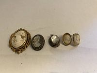 Front view of the jewelry set showing cameo brooch, pendant, ring, and earrings with detailed carved female profiles in silver settings.