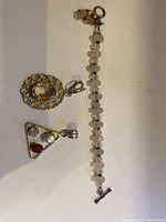 Top view of sterling silver pendants and beaded bracelet against white background