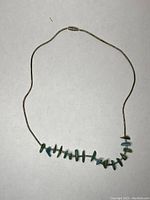 Full view of the necklace laid out to show overall design with turquoise chip stones on the silver chain