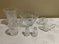Photo showing all crystal items arranged on a white tablecloth, including the Waterford Marquis bowl, vase, salt and pepper shakers, jam jar, cream and sugar set.