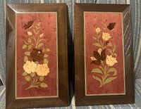 Front view of two intarsio wood inlaid floral pictures with reddish backgrounds and darker wood frames