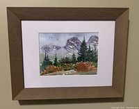 Framed watercolor painting of the Three Sisters mountains in the Rockies by Karen Richter, showing the full framed work hanging on the wall.