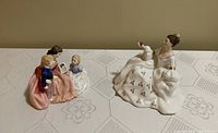 Two Royal Doulton porcelain figurines, "The Bedtime Story" with woman and children on left, "My Love" seated woman in white floral dress on right.