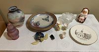 Wide view of all lot items displayed on table including vase, plates, figurines, and small carvings