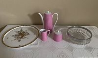Full view of the lot showing the Birks cake plate with gold decoration, pink coffee set with pot, creamer, and sugar bowl, and clear hobnail crystal bowl.