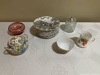 Overall lot showing 12 scenic brown transferware Myott Royal Mail dessert plates stacked, crystal silverplate jam jar, cranberry glass candy dish, floral Grimwades Royal Winton sugar bowl, and Radford cream and sugar set with leaf motifs.