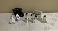 Photo showing six salt and pepper shakers of various materials and two vintage opera glass cases.
