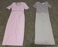 Two women's size 8 long dresses laid flat on the floor, one solid pink, the other with a beaded top and light skirt.