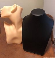 Front view of the two jewelry display neck forms: one black leatherette and one skin colored resin.