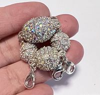 Hand holding four silver plated magnetic clasps adorned with AB Swarovski crystals, featuring lobster claw closures.