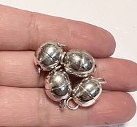 Four oval-shaped magnetic clasps held on fingers to show size and detail.