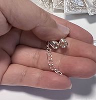 Close up showing silver plated lobster clasp and extension chain held in hand, illustrating size and detail.