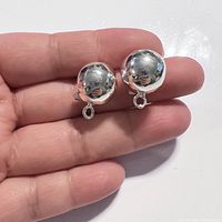 Two silver ball earring findings held on fingers showing size and reflective surface