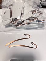 Two examples of antique copper plated brass bookmarks laid out, highlighting the hook and flat elongated design.