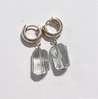 Pair of natural green amethyst dangling earrings with 18k gold plated hoops displayed flat.
