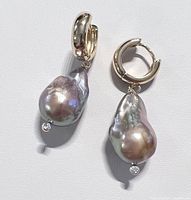 Pair of grey baroque freshwater pearl earrings with gold plated chunky hoops and hanging clear stone detail, shown against white background.