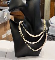 Necklace displayed on a black bust with three layered strands showing alternating sections of pearls and gold plated chain
