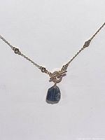 Necklace displayed on white background focusing on pendant and chain with cubic zirconia accents on toggle clasp.