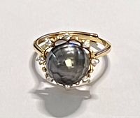 Top view of the ring showing the faceted black pearl surrounded by clear cubic zirconia stones, gold-tone setting and band.
