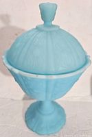 Blue frosted glass lidded compote showing embossed patterns and scalloped edges
