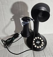 Front view of black Crosley CR64 candlestick telephone showing rotary dial and handset resting beside the upright base.