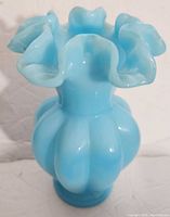 Front and side view of blue opalescent melon style vase with ruffled top.