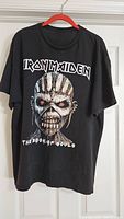Front view of black Iron Maiden concert T-shirt featuring Eddie graphic and band name with The Book of Souls text.