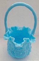 Front view of blue Fenton glass basket showing ruffled top and handle