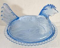 Photo showing blue glass hen figurine with textured feathers and comb, sitting on a nest base with beaded rim.