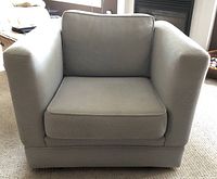 Front view of light gray fabric armchair showing cushioned seat, back, and armrests