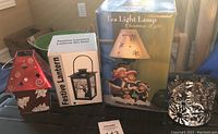 Lot of four Christmas candle holders including red metal holder, festive lantern, ceramic lamp with bears, and chrome snowflake metal holder.